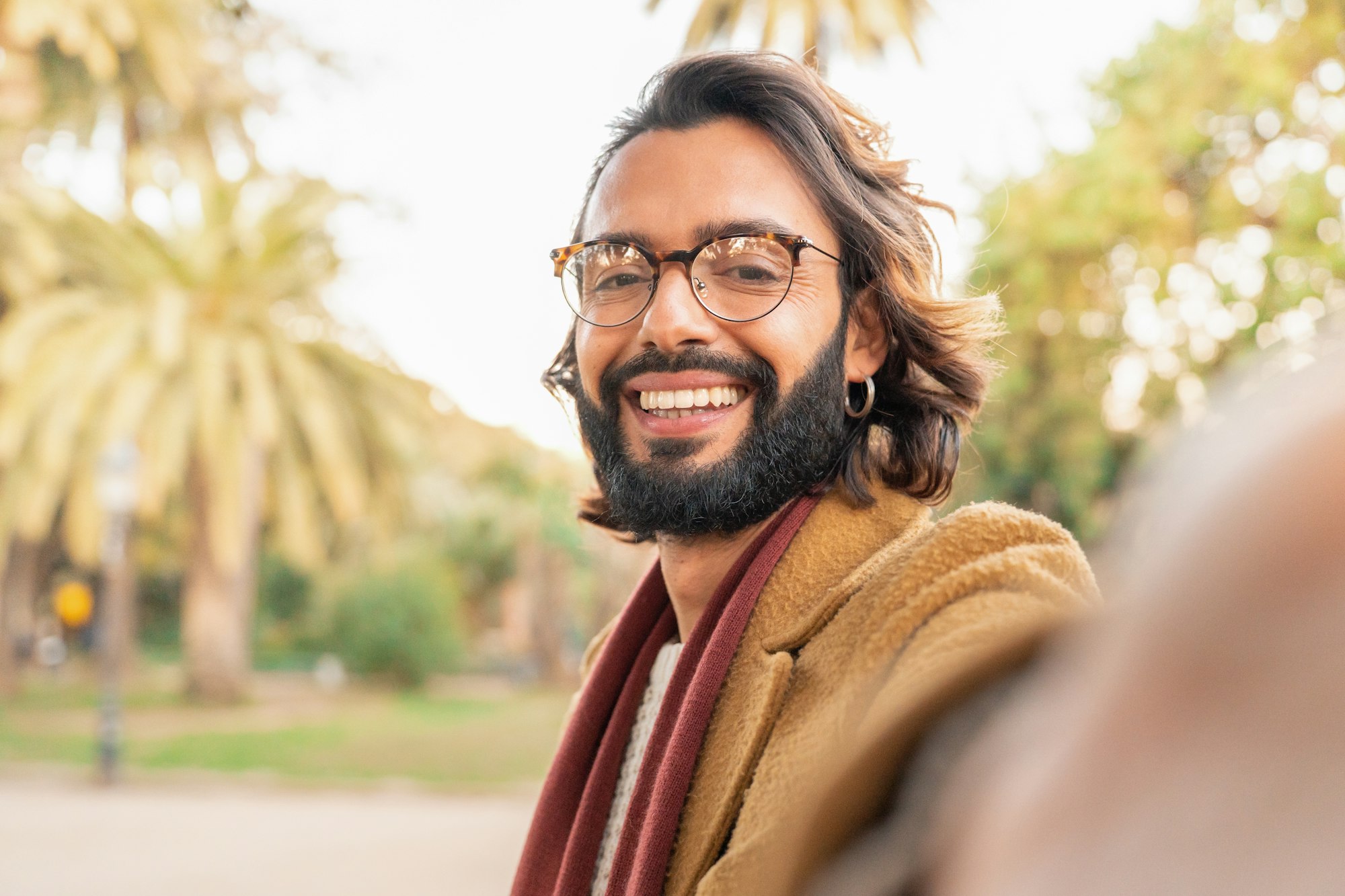 attractive-man-with-glasses-and-beard-taking-a-selfie-smiling-outdoors-in-the-park- Home